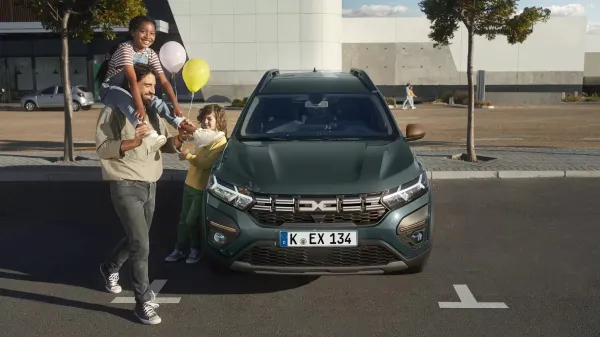 Dacia Jogger auf einem Parkplatz mit einem Vater und zwei Kindern